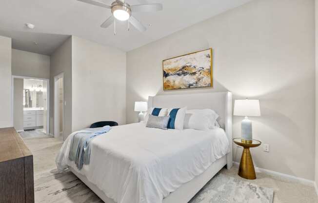 a white bedroom with a white bed and a ceiling fan