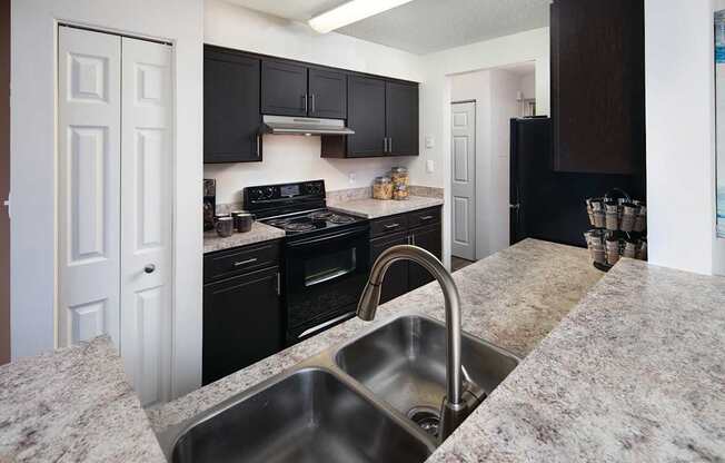 A kitchen with granite countertops and black cabinets.