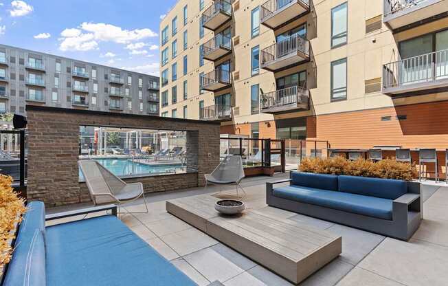A modern outdoor seating area with a pool and a brick wall.