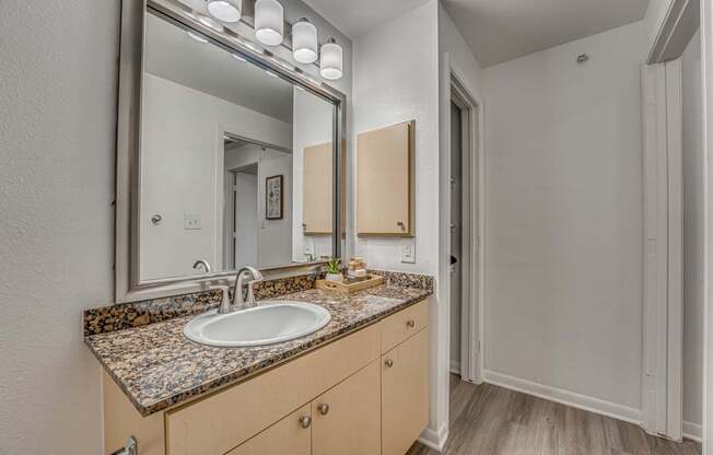 A bathroom with a sink, mirror, and wooden cabinets.