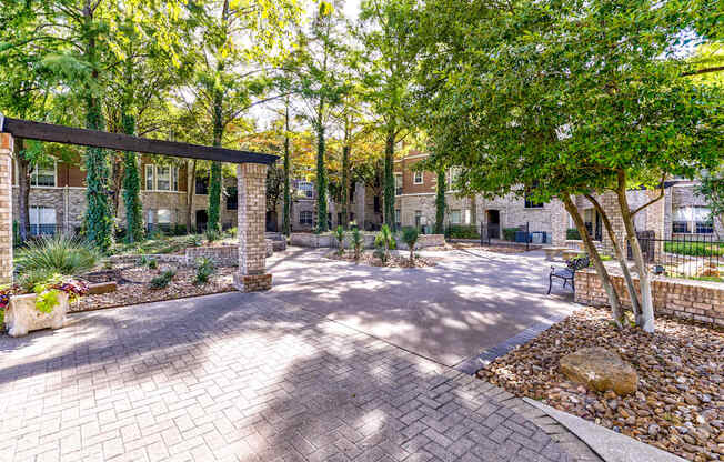 A courtyard with a brick walkway and a tree in the center.