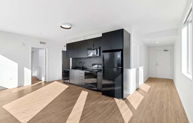 A modern kitchen with black cabinets and a black fridge.