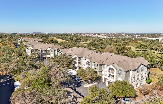 A large, multi-story residential building surrounded by trees.