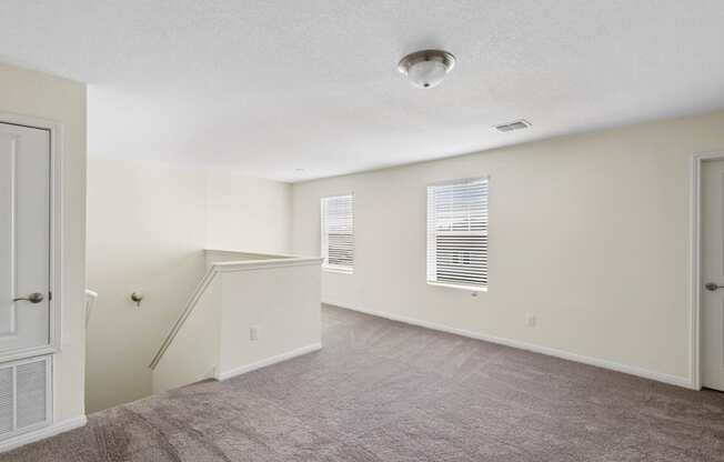 loft room with a staircase, carpeted floor and two windows