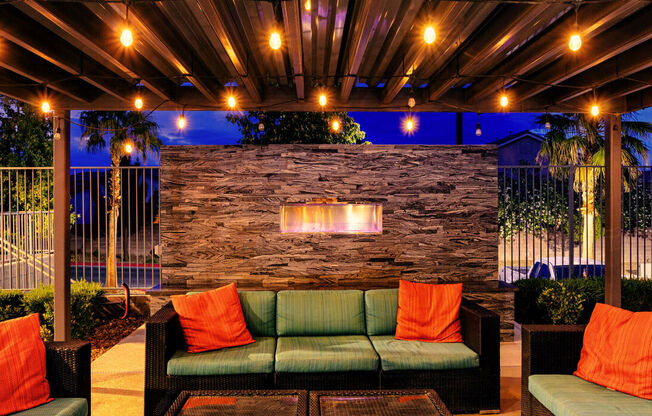 A patio with a stone wall and a fireplace.