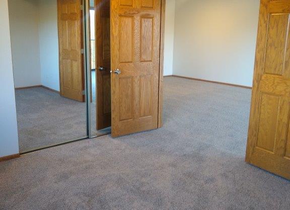 A room with carpeted floor and three doors.