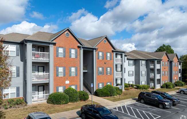 Apartment complex with a parking lot in front.