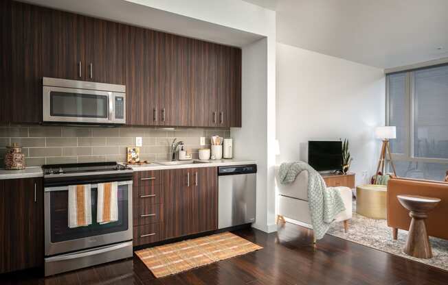 a kitchen and living room with wooden cabinets and stainless steel appliances