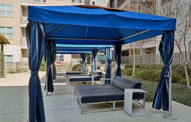 A blue canopy with curtains and a bench underneath it.