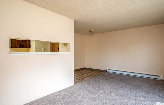 A room with a carpeted floor and a window with blinds.