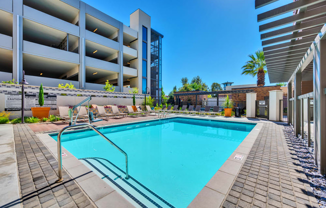 A swimming pool surrounded by a brick walkway and a metal fence.