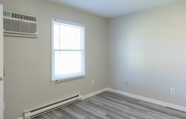 A room with a window and a wall-mounted air conditioner.