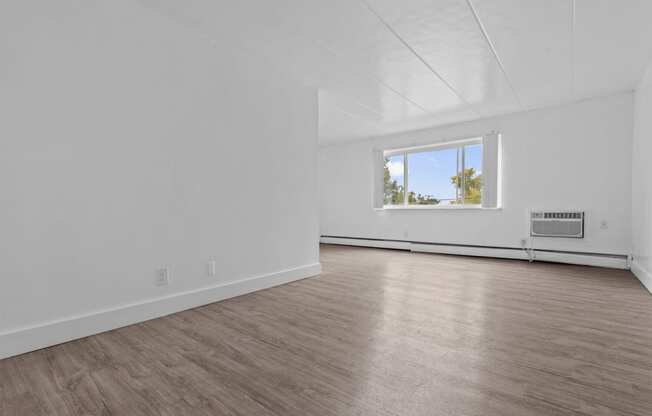 an empty living room with white walls and a window