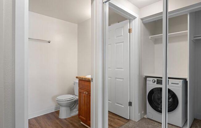 a bathroom with a toilet and a washing machine in a closet