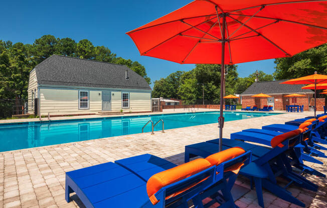 a swimming pool with blue tables and umbrellas next to a house