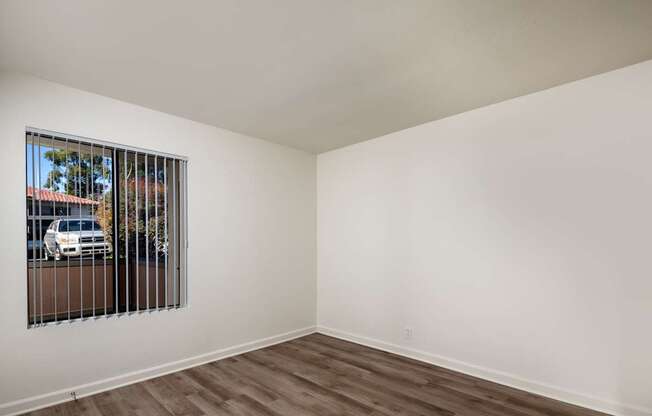 A room with a window and a white wall.