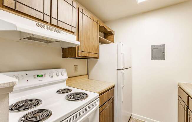 A white stove and refrigerator in a kitchen with wooden cabinets