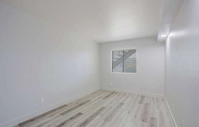 a bedroom with hardwood floors and white walls