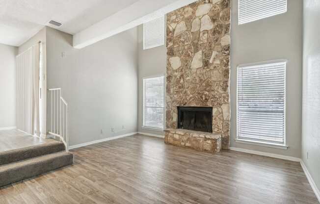 the living room has a large stone fireplace and hardwood floors