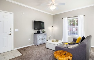 a living room with a ceiling fan and a tv on the wall