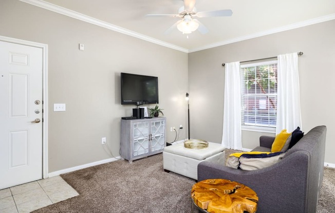 a living room with a ceiling fan and a tv on the wall