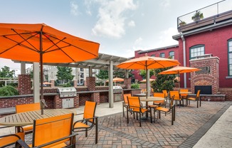 View of Grilling Lounge, Showing Grills, Pergola, and Picnic Areas with Umbrellas at Alpha Mill Apartments