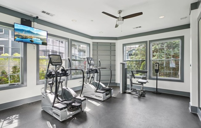 A spacious room with exercise equipment and a television displaying a beach scene.