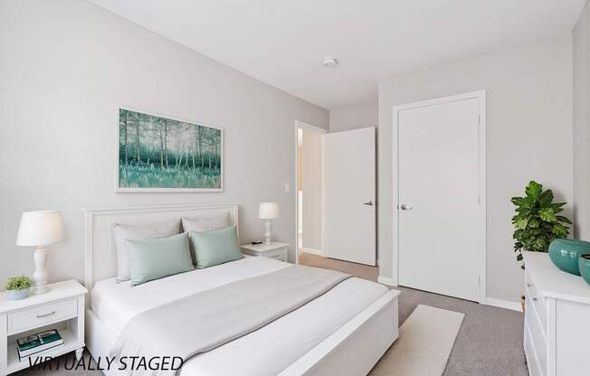 A bedroom with a large bed, two lamps, and a painting on the wall.