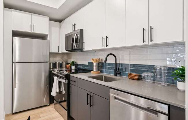 A modern kitchen with a stainless steel refrigerator and black cabinets.
