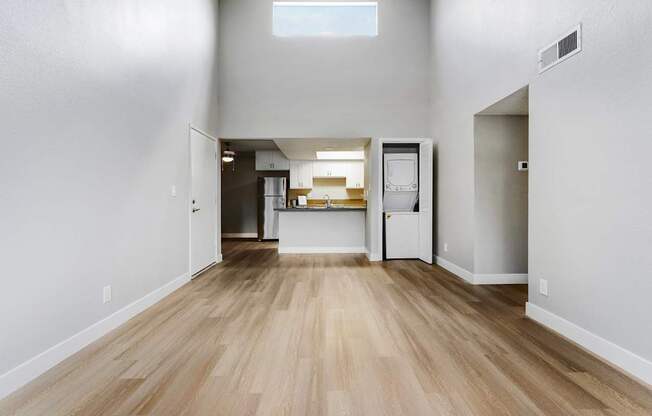 the living room and kitchen of an empty apartment with wood flooring