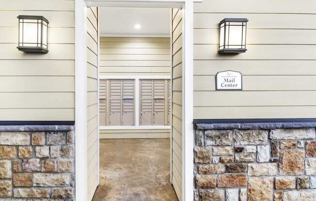 the entrance to a building with a stone wall and a door to the mail center