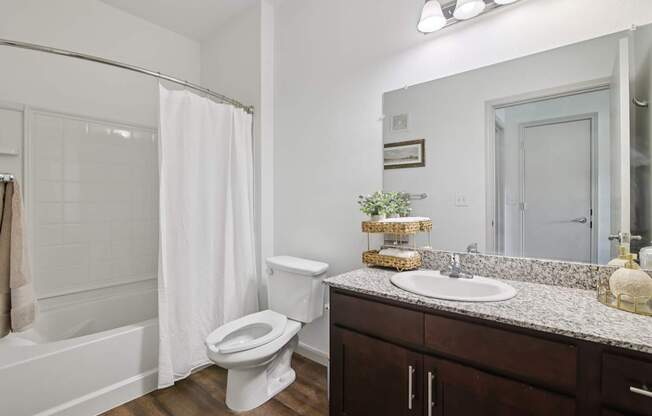 A white toilet sits in a bathroom with a white shower curtain.