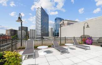 A rooftop patio with a table and chairs overlooking a city skyline.
