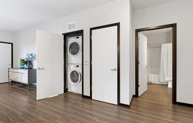 a washer and dryer in a living room with a door to a bathroom