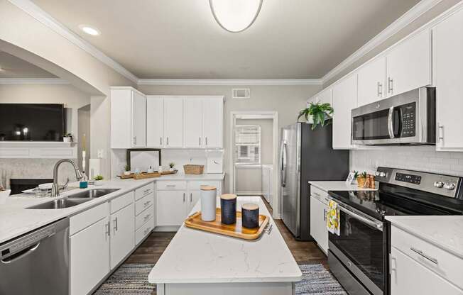 A modern kitchen with white cabinets and stainless steel appliances.