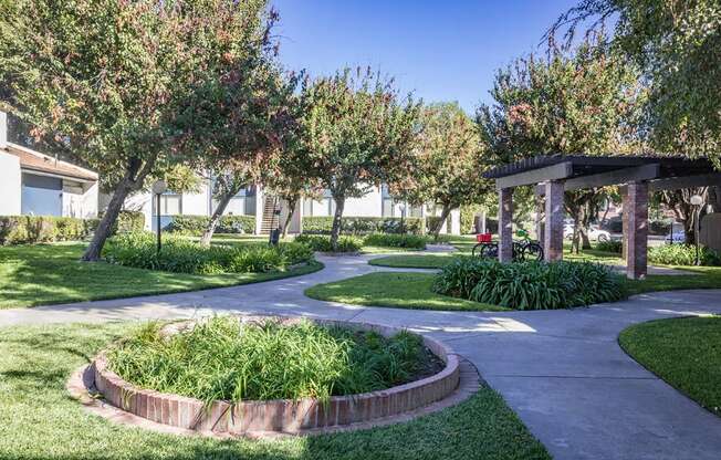 A garden with a circular flower bed and a wooden pergola.