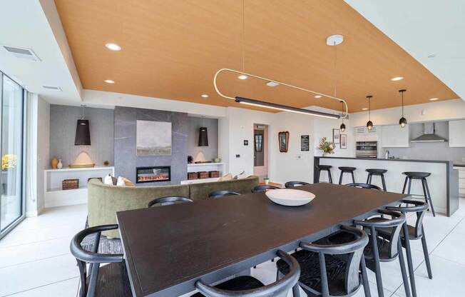A modern kitchen with a wooden ceiling and a dining table with chairs.