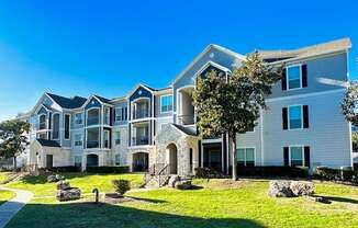 an apartment building with grass and trees in front of it