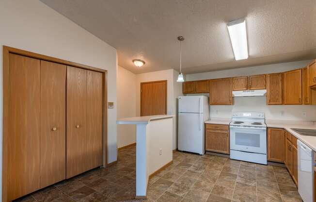 a kitchen with white appliances and wooden cabinets.  Fargo, ND Sunwood Apartments  | Living and kitchen Fargo, ND Sunwood Apartments