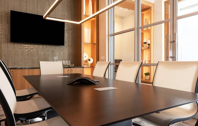 a conference room with a table and chairs and a tv on the wall