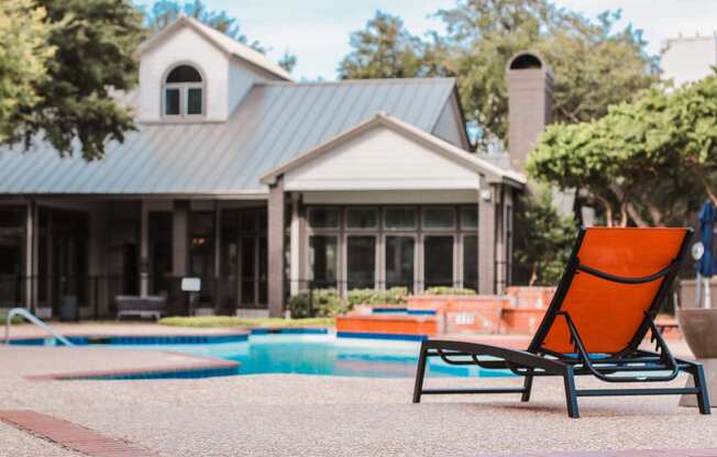 a pool chair in front of a house with a swimming pool