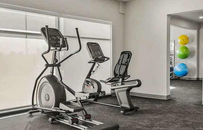 A gym with a treadmill, elliptical trainer and a stationary bike.