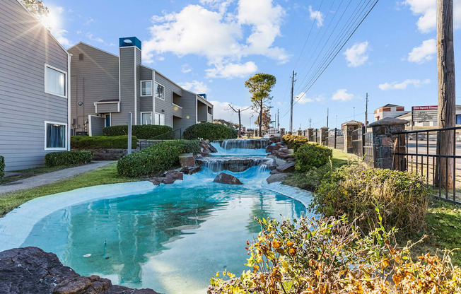 a small pool with waterfalls in front of apartment buildings