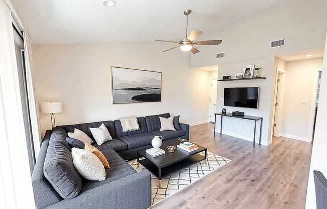 A living room with a grey couch and a painting on the wall.