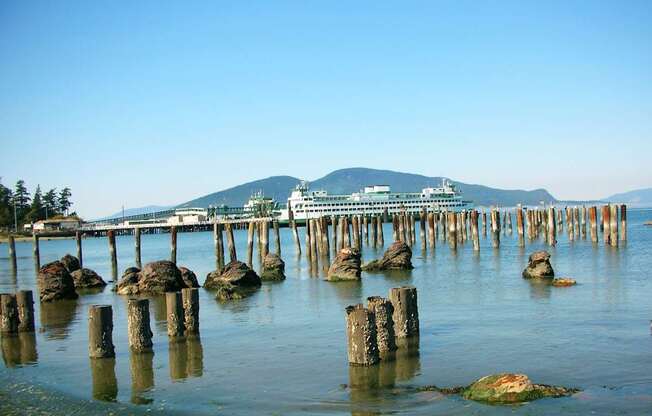 A pier extends into a calm body of water with a mountain in the distance.