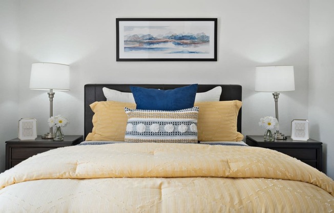 a bedroom with a bed with yellow and blue pillows
