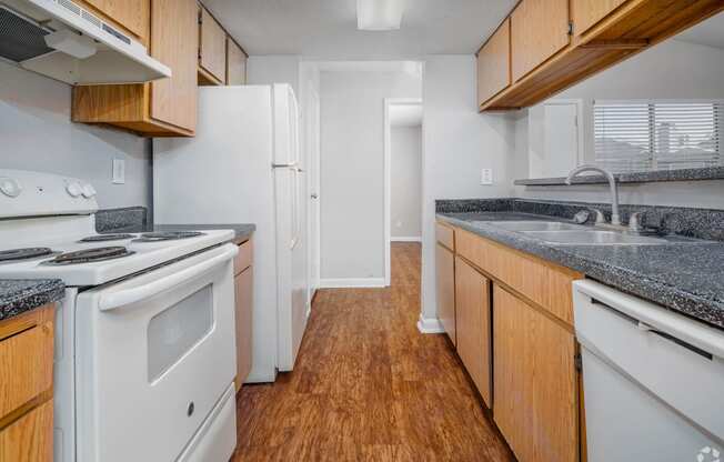 an empty kitchen with white appliances and wood cabinets