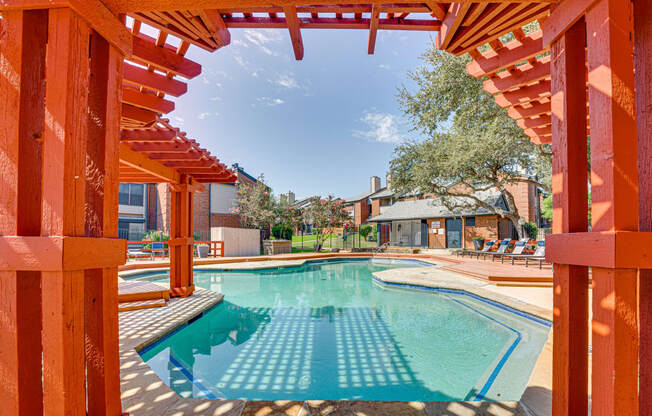 a swimming pool with wooden structures around it and houses in the background