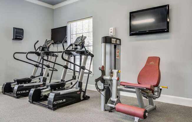 A home gym with a treadmill, elliptical trainer, and a stationary bike.