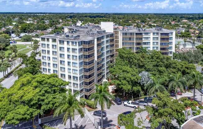 an aerial view of a tall building surrounded by trees and a parking lot